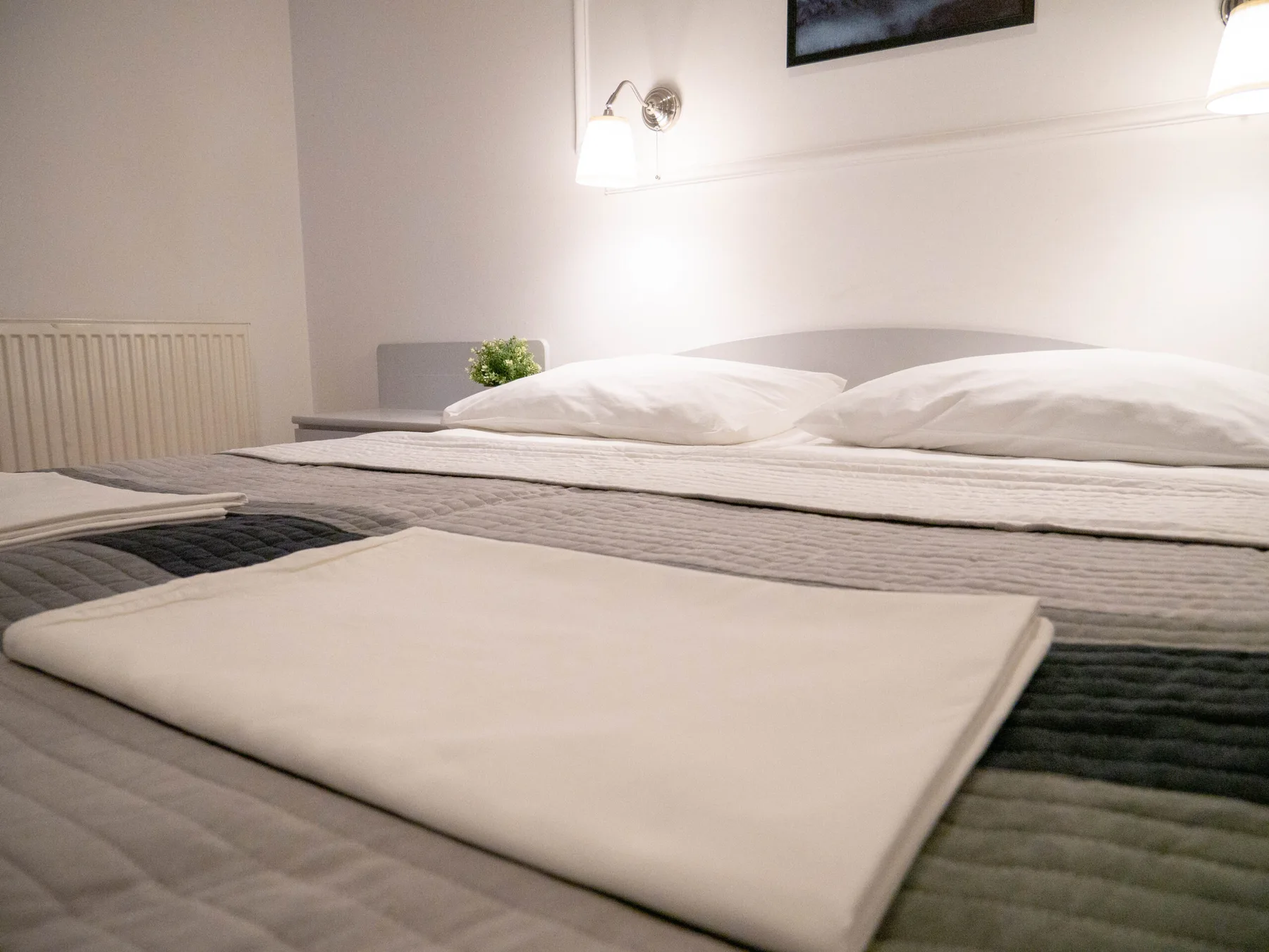 Espacio representativo del hotel: Un dormitorio con una cama arreglada y ropa de cama doblada.