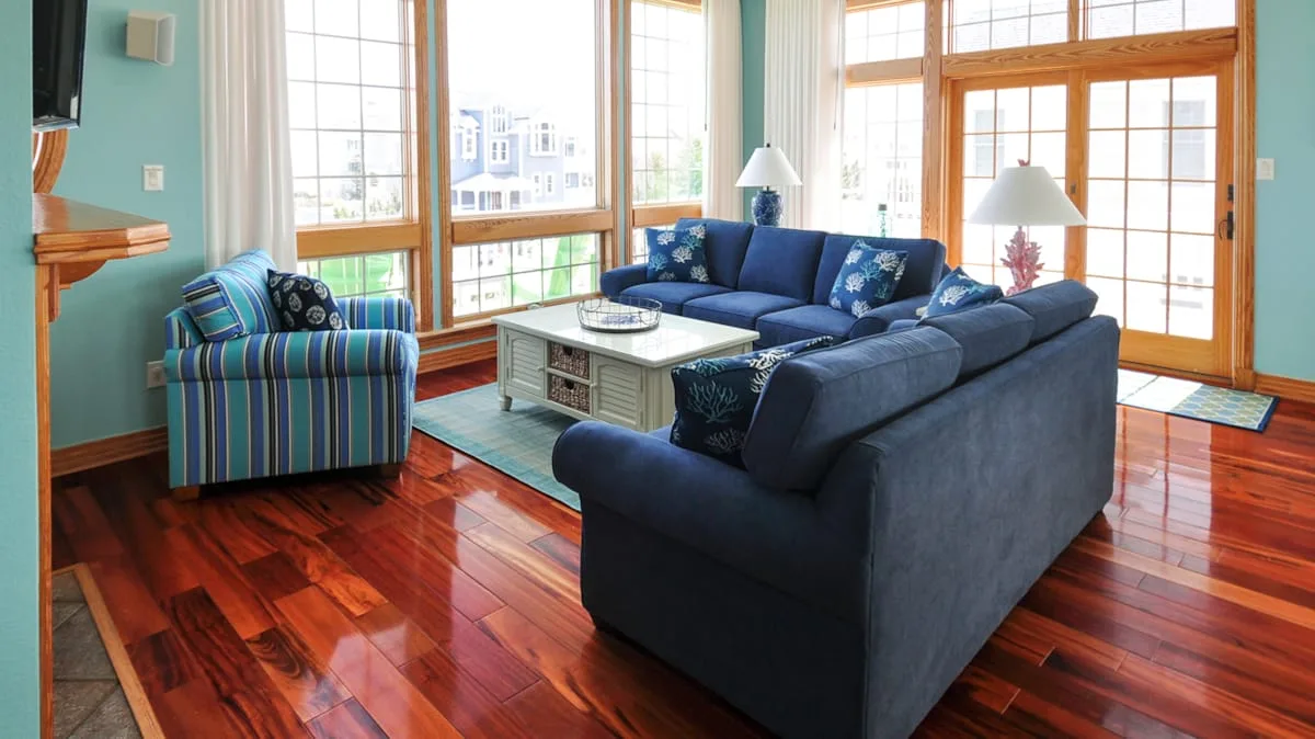 A living room with blue seating, a coffee table, and large windows.