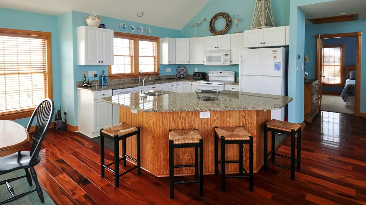 A bright kitchen with a central island and white cabinets.