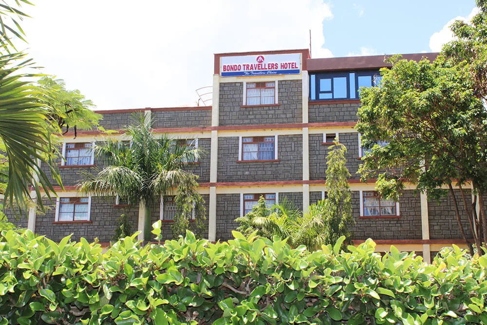 Representative hotel space: Hotel building with rows of windows, surrounded by trees and shrubs.