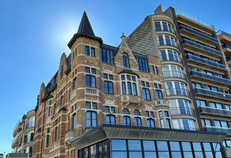 Espacio representativo del hotel: Un edificio de ladrillo ornamentado se alza junto a una torre moderna bajo un cielo despejado.