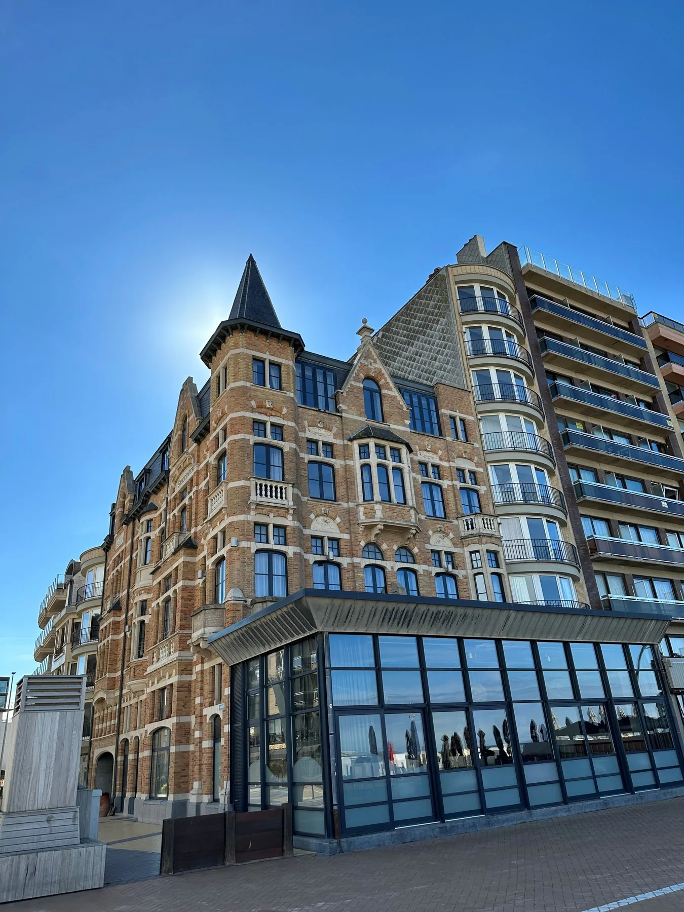 Espacio representativo del hotel: Un edificio de ladrillo con una torre puntiaguda está junto a un edificio moderno con fachada de vidrio.