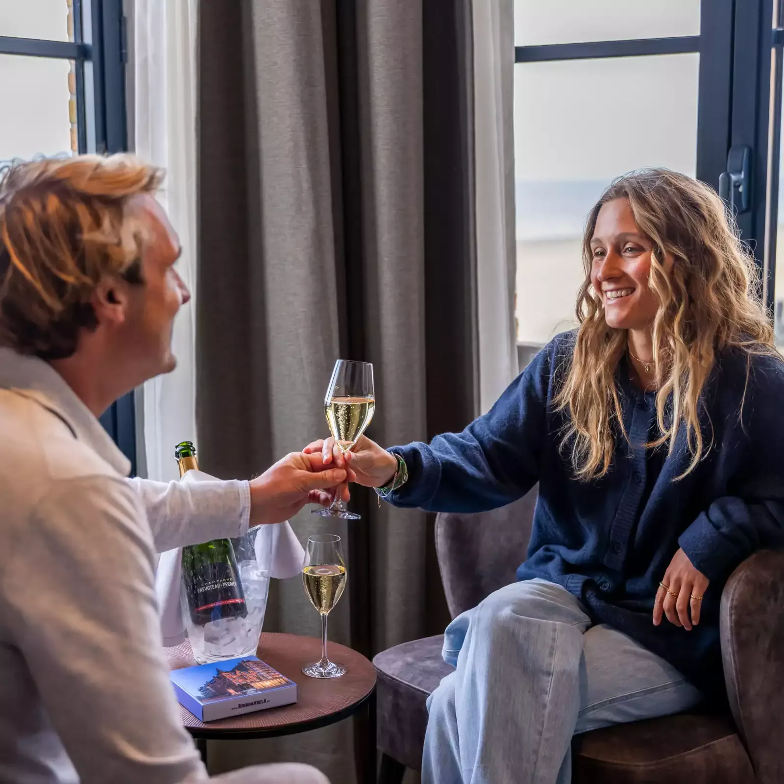 Espacio representativo del hotel: Dos personas brindan con vino sentadas junto a una ventana.