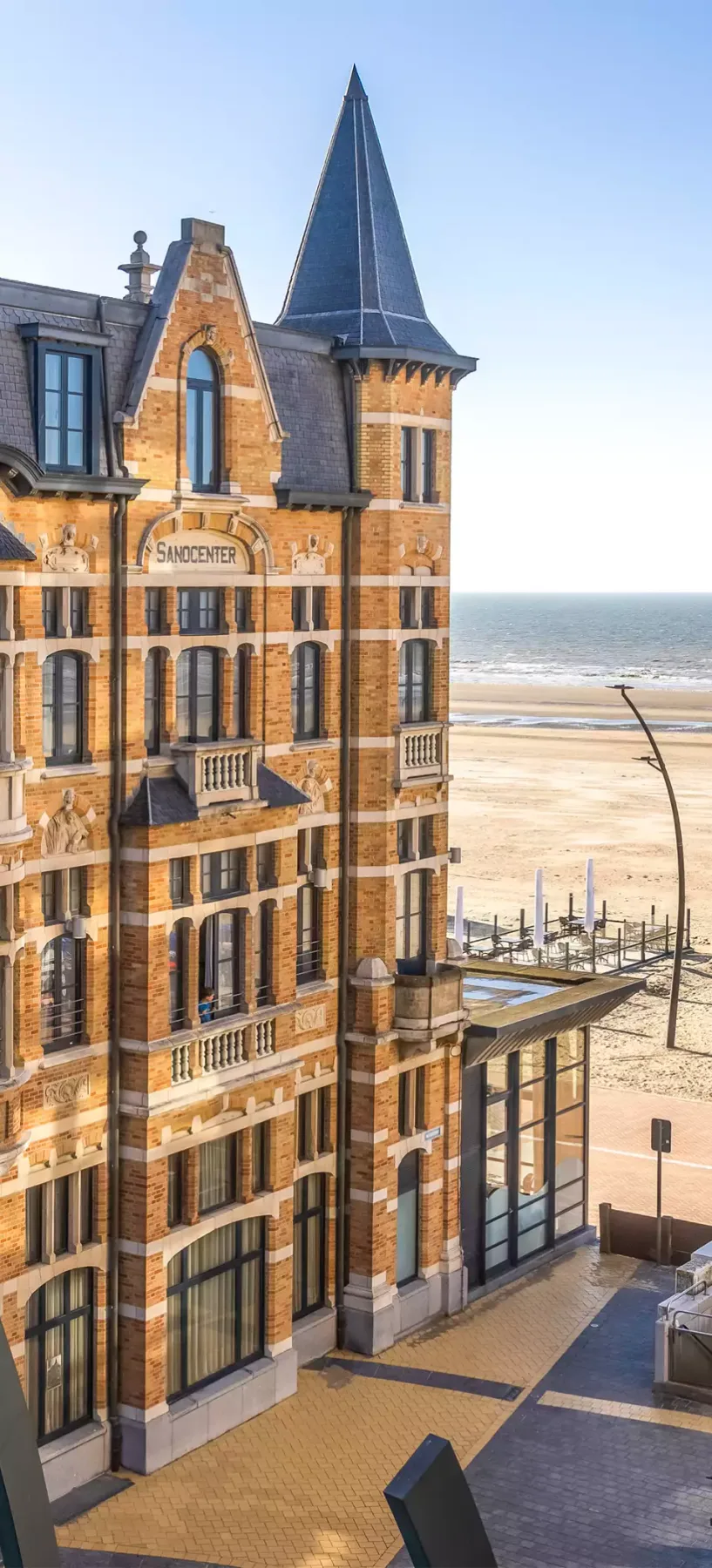 Espacio representativo del hotel: Un edificio hotelero de ladrillo está junto a una playa de arena y el mar.