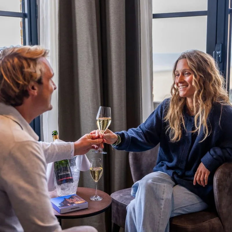 Espacio representativo del hotel: Dos personas brindan con vino sentadas junto a una ventana.