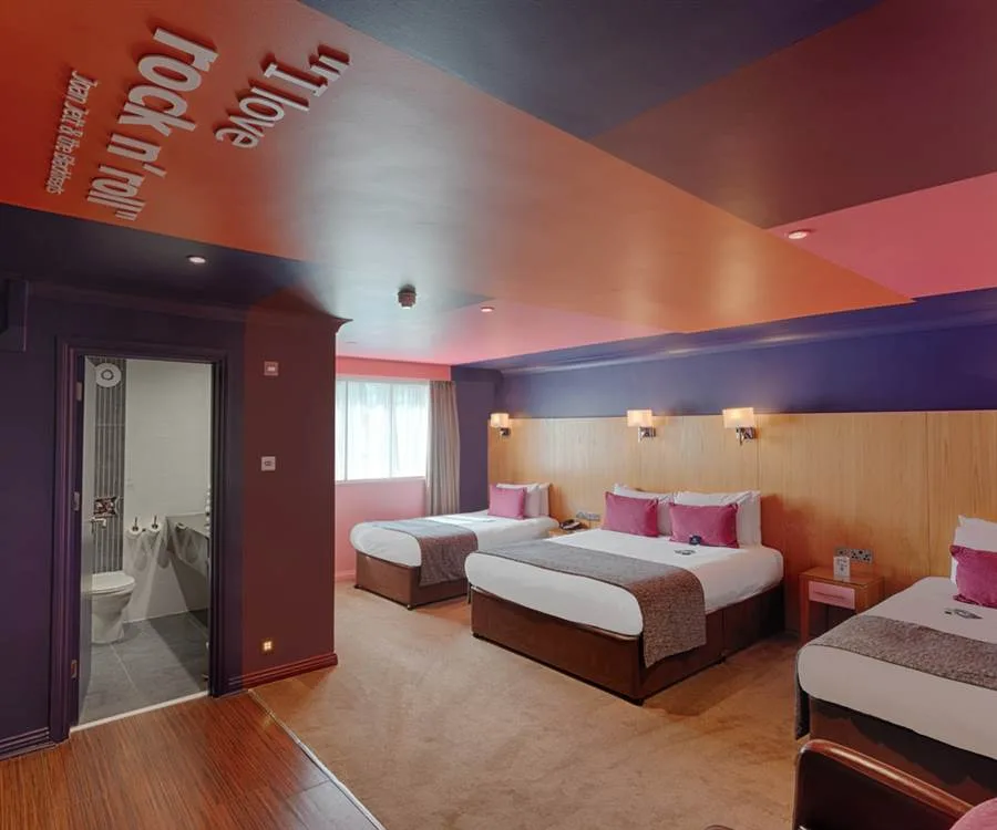 Representative hotel space: A hotel bedroom with several beds and a wood-paneled headboard wall.