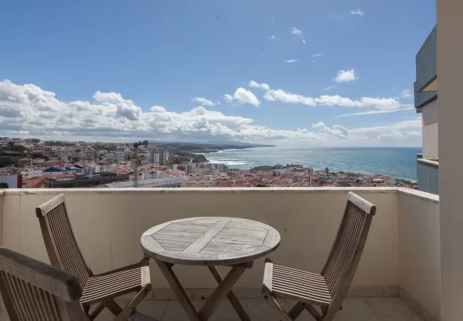 Una zona de estar en un balcón da a un pueblo costero y al mar.
