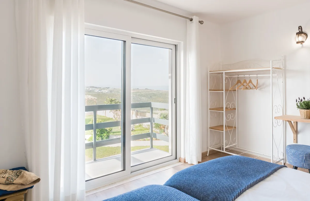 Espacio representativo del hotel: Un dormitorio luminoso con una cama junto a grandes puertas corredizas de vidrio.