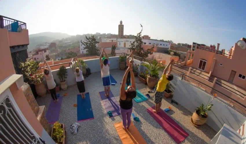 Espacio representativo del hotel: Varias personas se estiran sobre esterillas de yoga en una terraza soleada.
