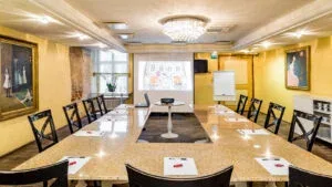 Espacio representativo del hotel: Una sala de reuniones con una mesa larga, sillas y una pantalla de proyección.