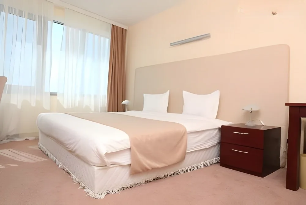 Representative hotel space: A bedroom with a neatly made bed beside a large window.