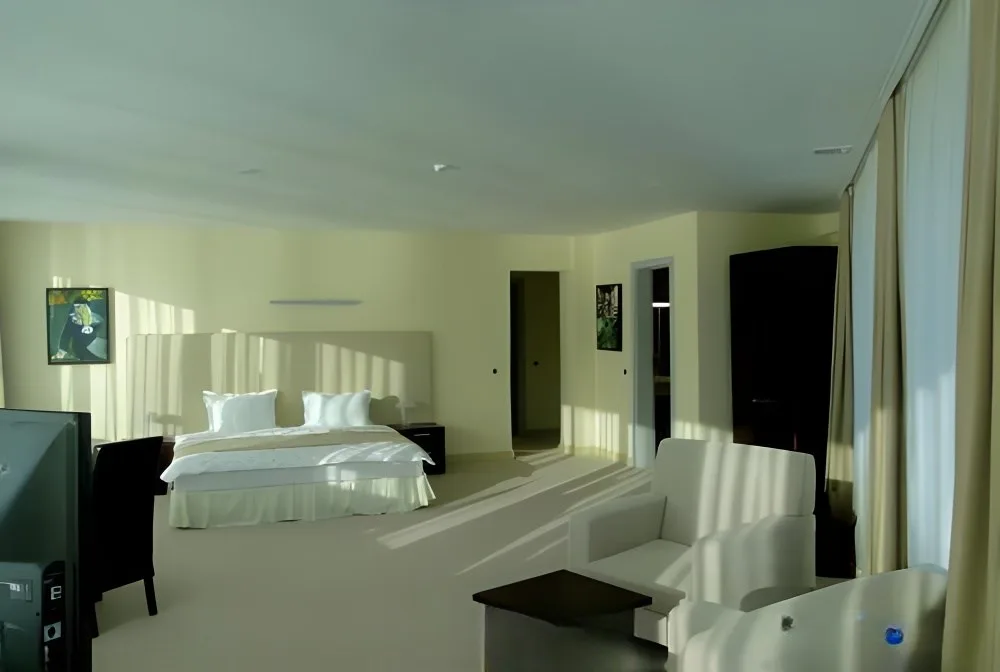 Representative hotel space: A bright hotel bedroom with a bed and seating beside large windows.