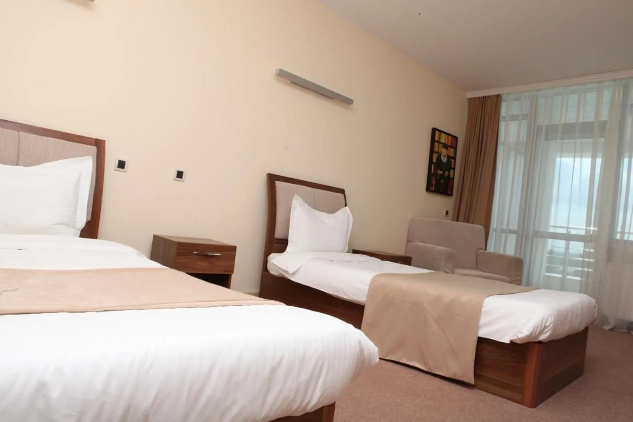 Representative hotel space: A hotel bedroom with two beds and a large curtained window.