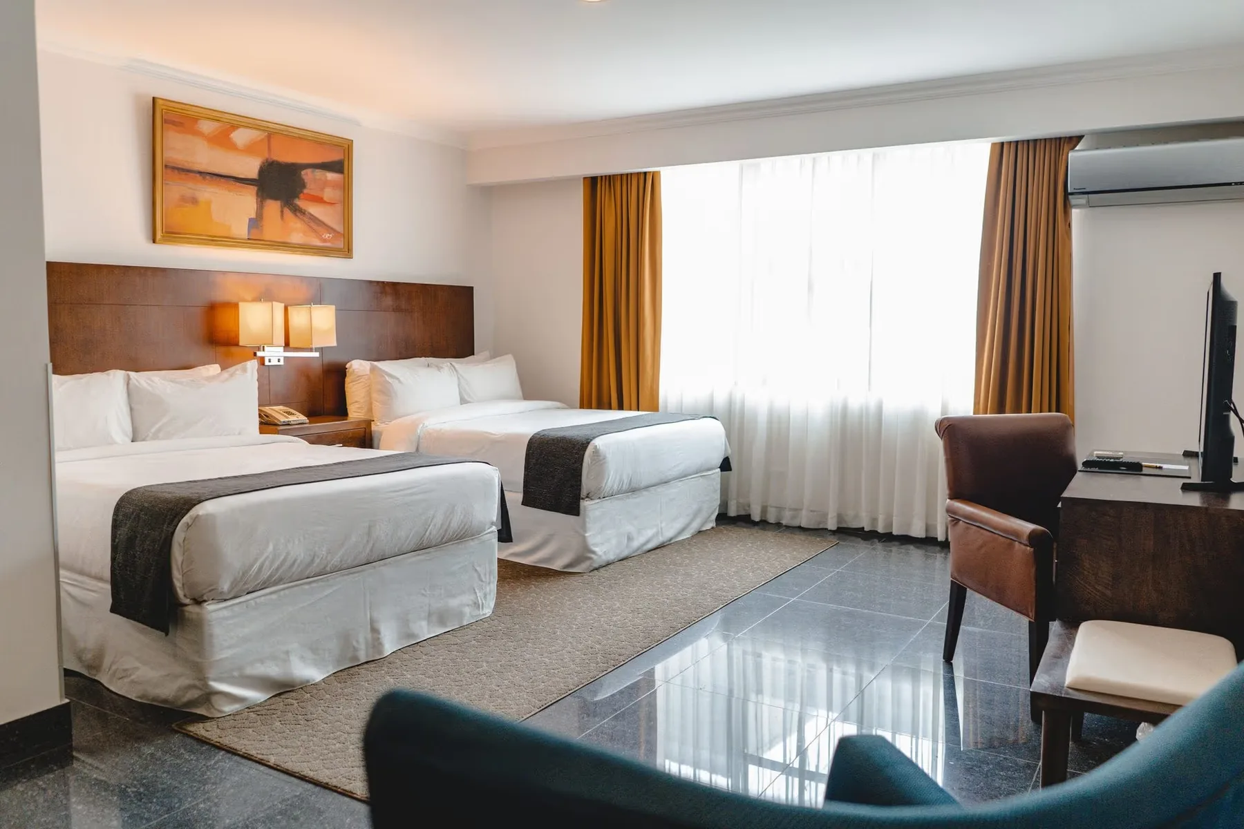 Representative hotel space: A guest room with two beds, a large window, and seating.