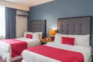 Representative hotel space: A hotel bedroom with two beds, red bedding, and a window with curtains.