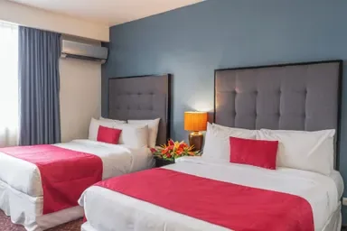 Representative hotel space: A bedroom with two beds dressed in white and red linens.