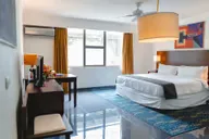 Representative hotel space: A hotel bedroom has a bed beside a desk and large windows.