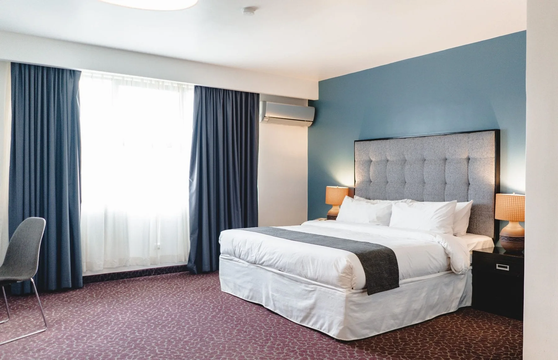 Representative hotel space: A bedroom with a large bed, dark curtains, and a blue accent wall.