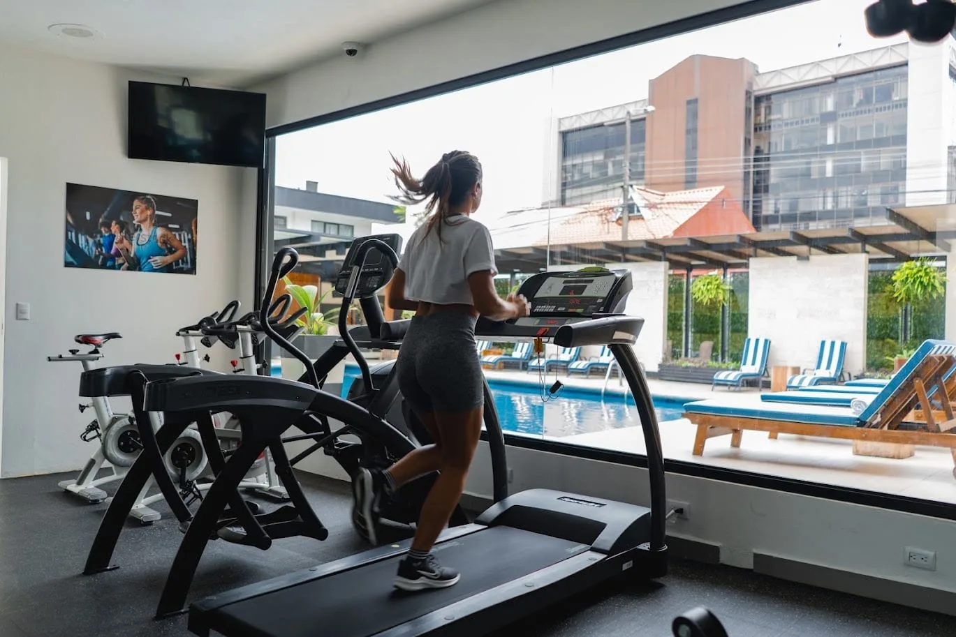 Representative hotel space: A hotel fitness room has treadmills and exercise equipment beside large windows.