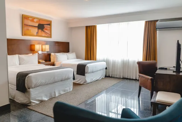 Representative hotel space: A hotel bedroom with two beds beside a bright curtained window.
