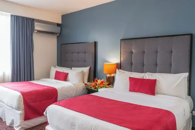 Representative hotel space: A hotel bedroom with two beds and red bedding against a blue wall.