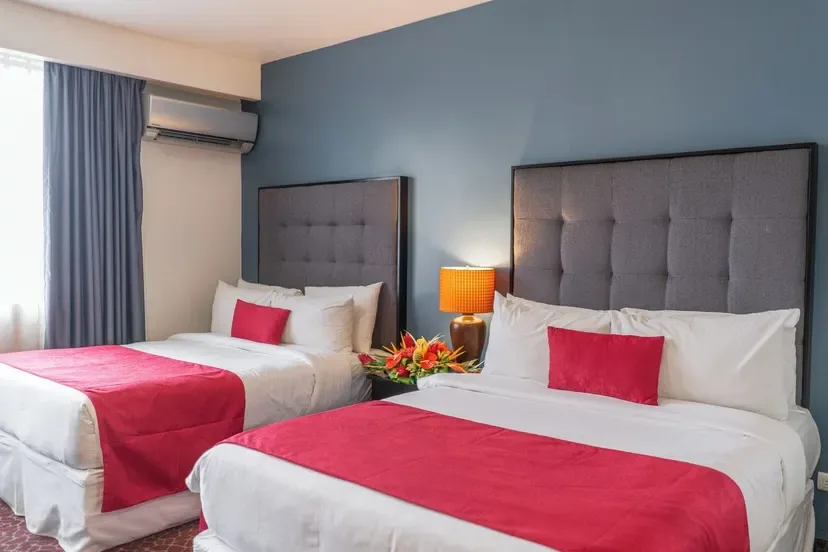 Representative hotel space: A hotel bedroom with two beds dressed in white and red linens.
