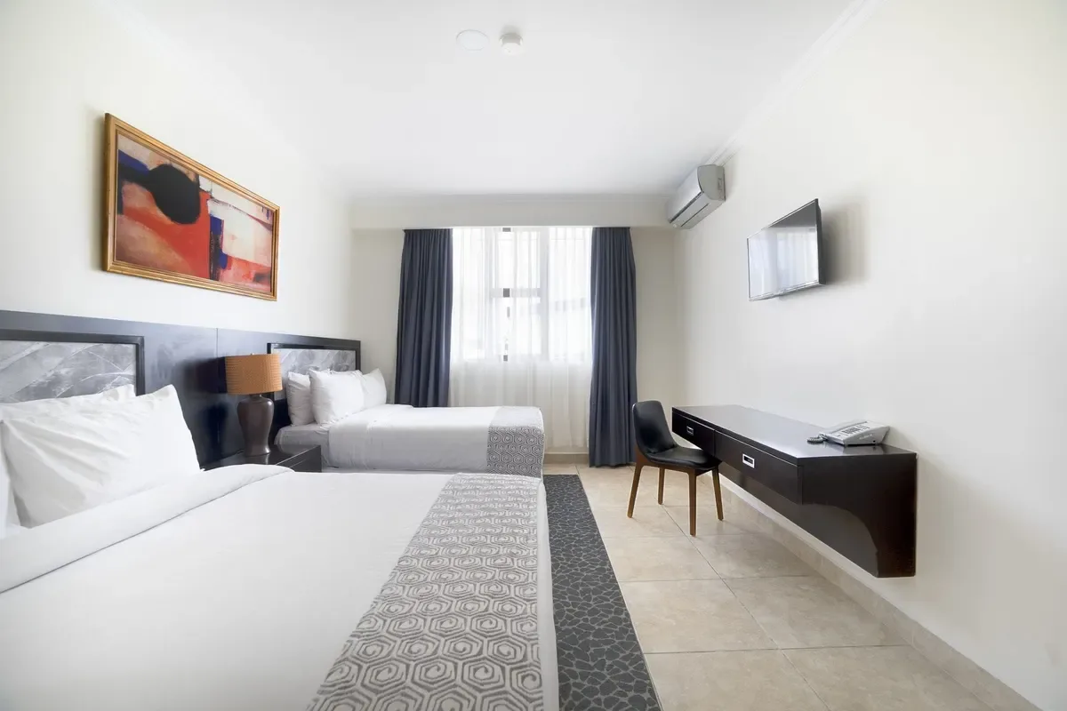 Representative hotel space: A bright hotel bedroom with two beds, a desk, and a window.
