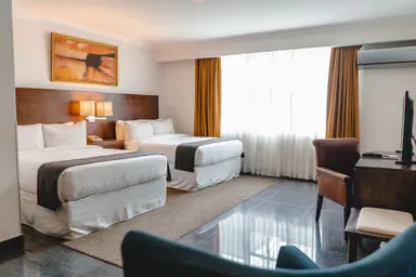 Representative hotel space: A hotel bedroom with two beds, a bright window, and seating.