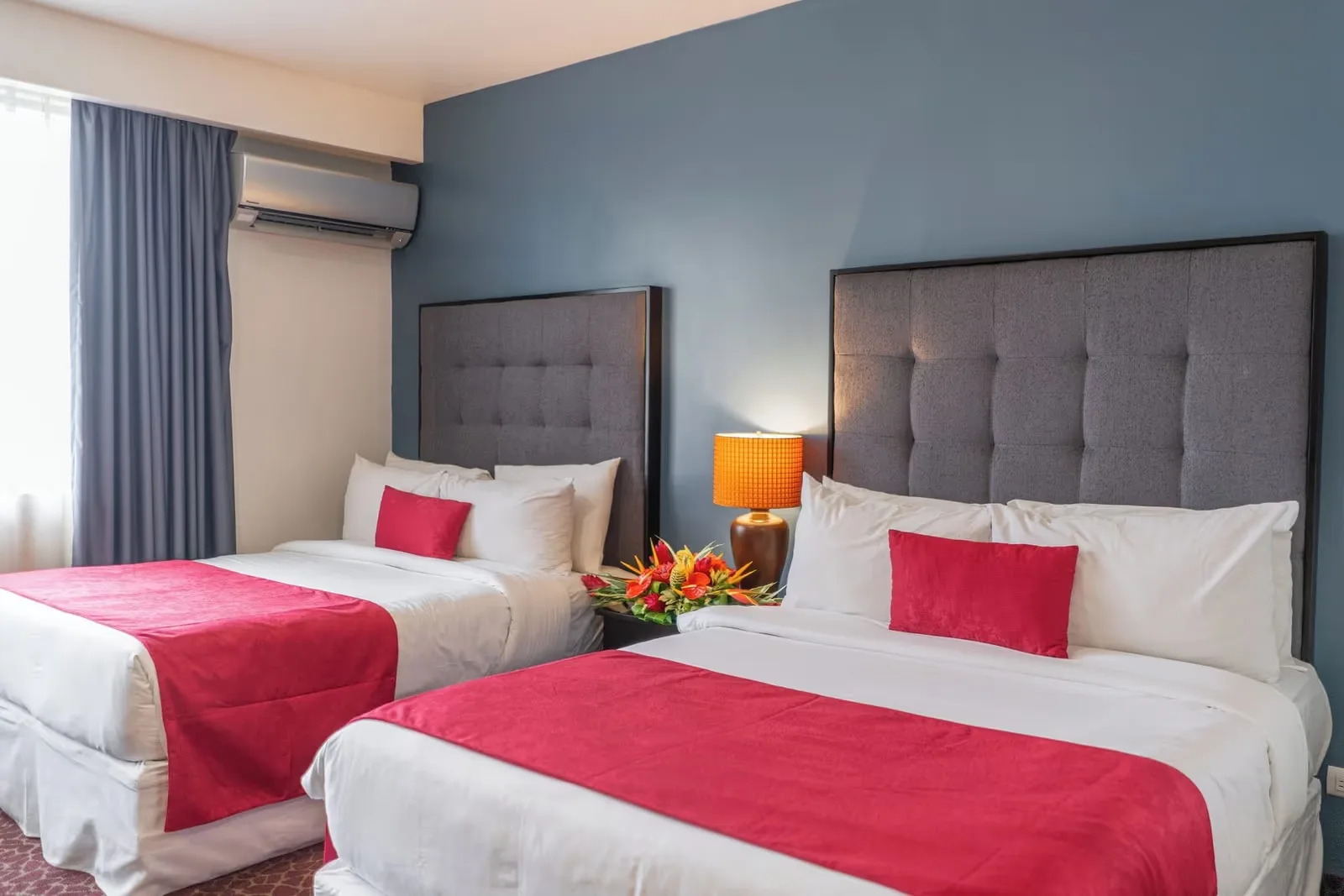 Representative hotel space: Hotel bedroom with two beds dressed in white linens and red runners.
