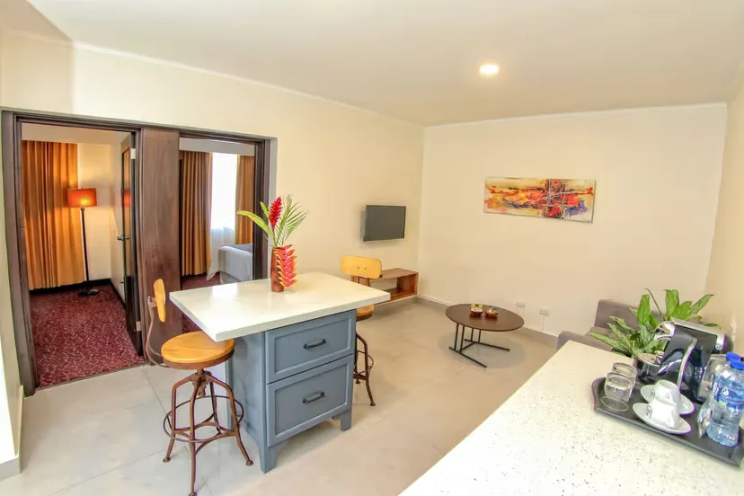 Representative hotel space: A dining area with a table and stools beside an open living space.