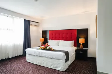 Representative hotel space: A hotel bedroom with a bed, red upholstered headboard, and bedside lamps.