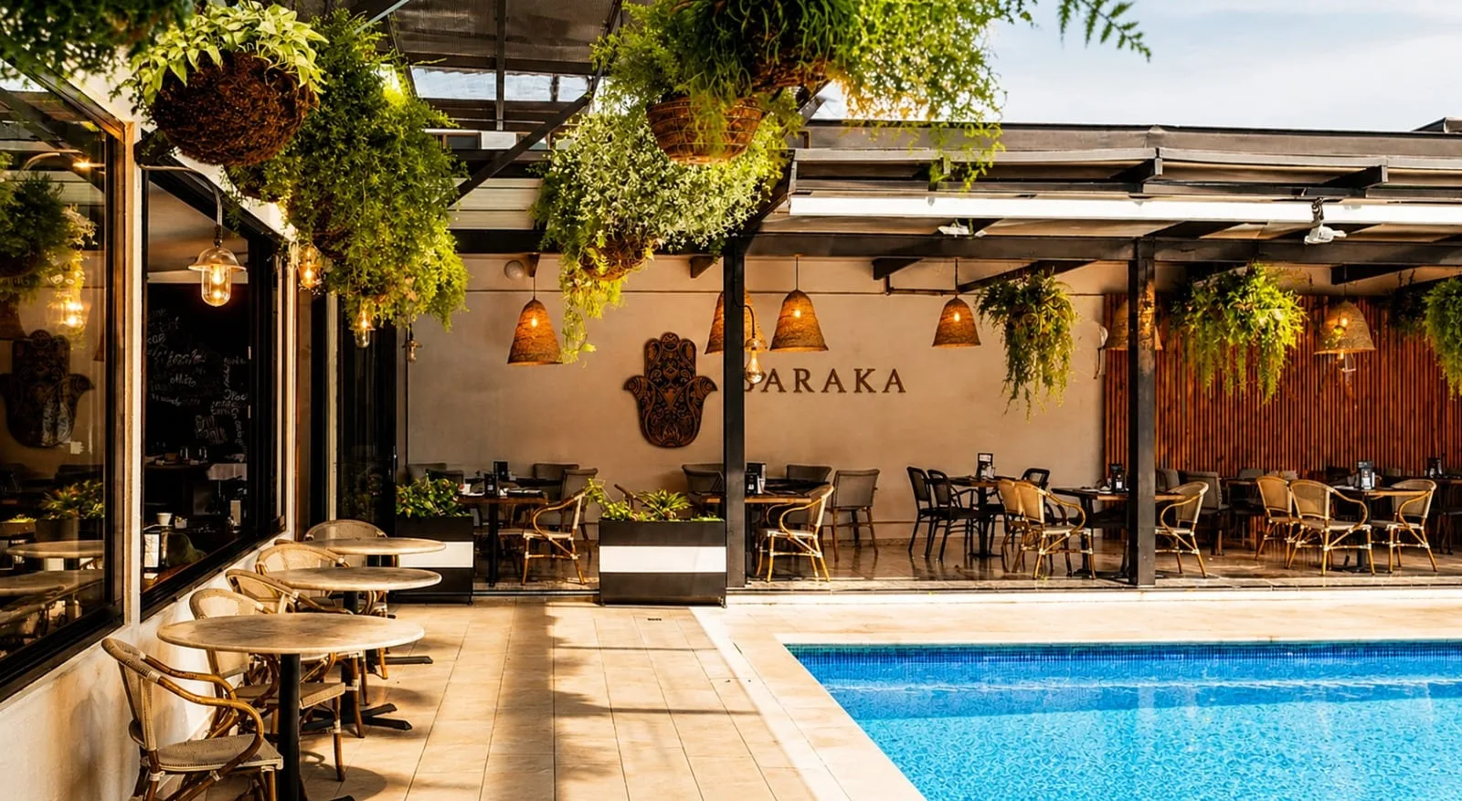 Representative hotel space: A poolside dining patio with tables beneath hanging greenery.