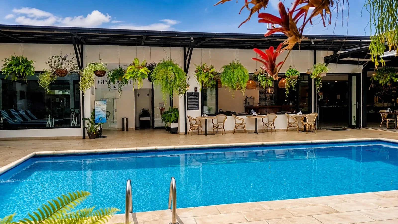Representative hotel space: An outdoor swimming pool sits beside a plant-lined building and seating area.