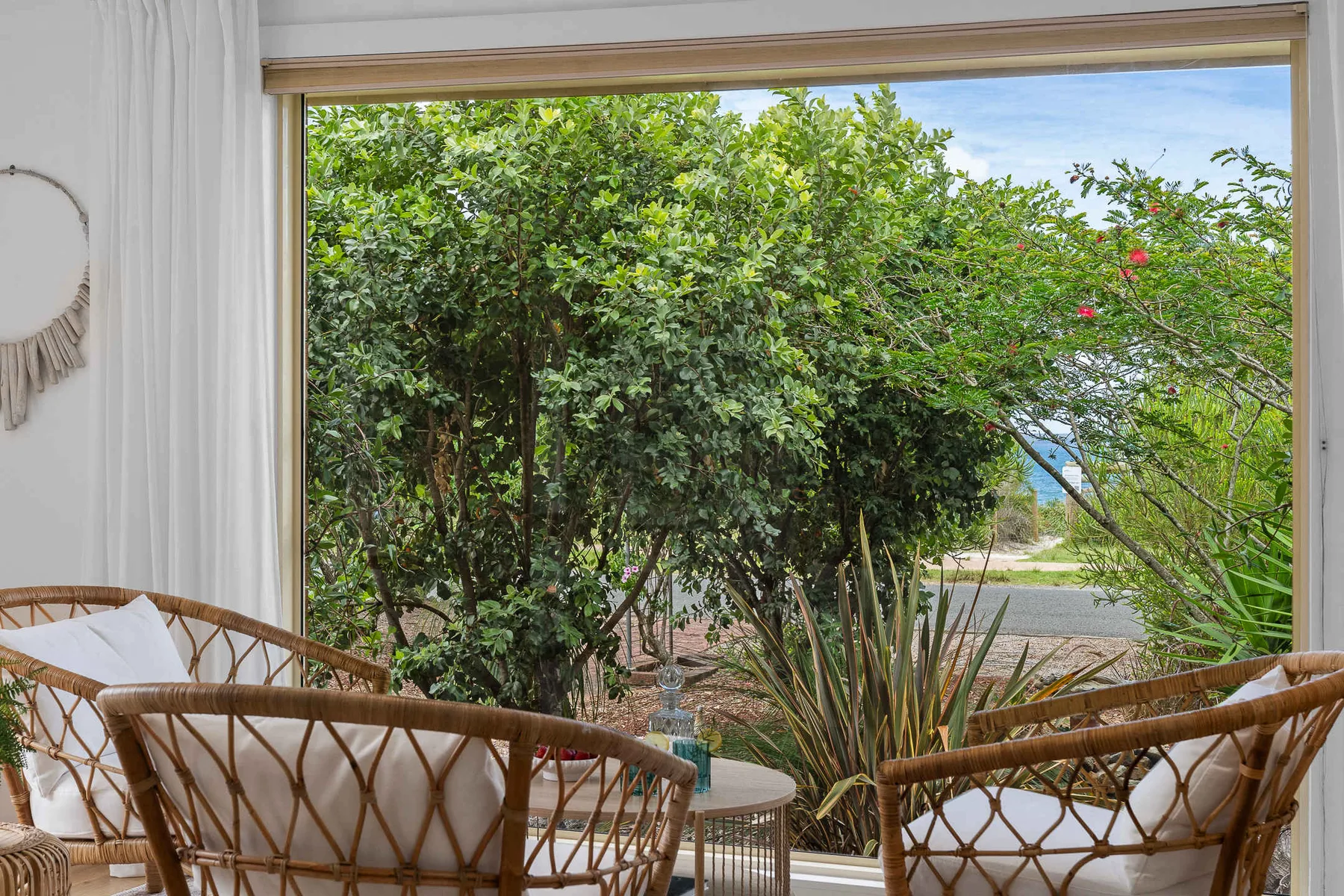 A seating area faces a large window overlooking leafy greenery and a glimpse of water.
