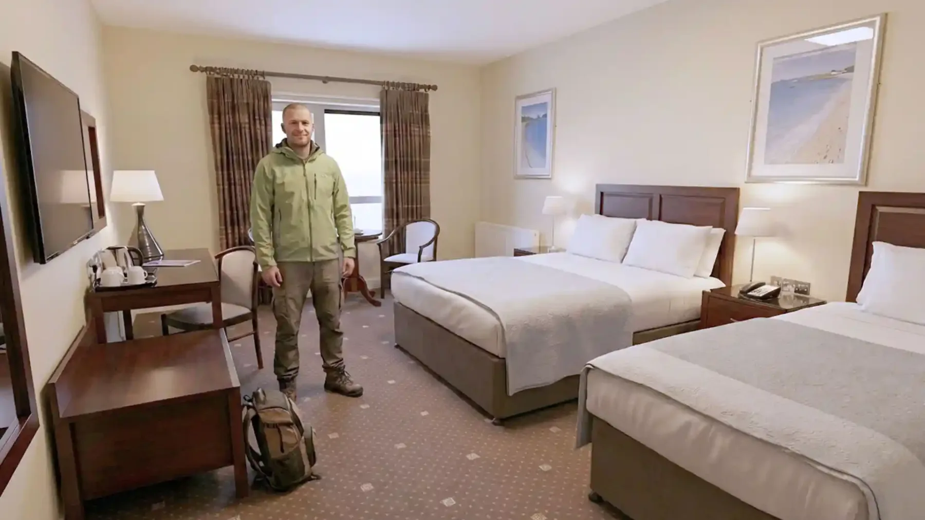 Espacio representativo del hotel: Un dormitorio de hotel con dos camas, mesillas y un televisor montado en la pared.