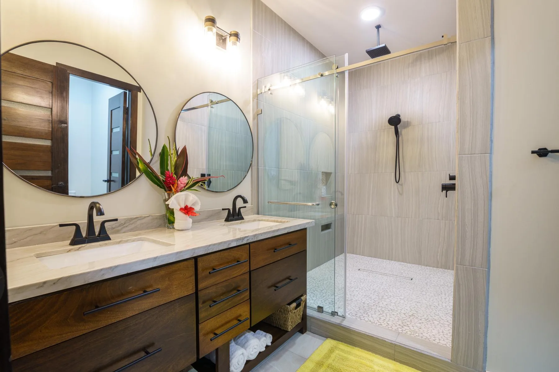 A bathroom vanity with mirrors sits beside a glass-enclosed shower.