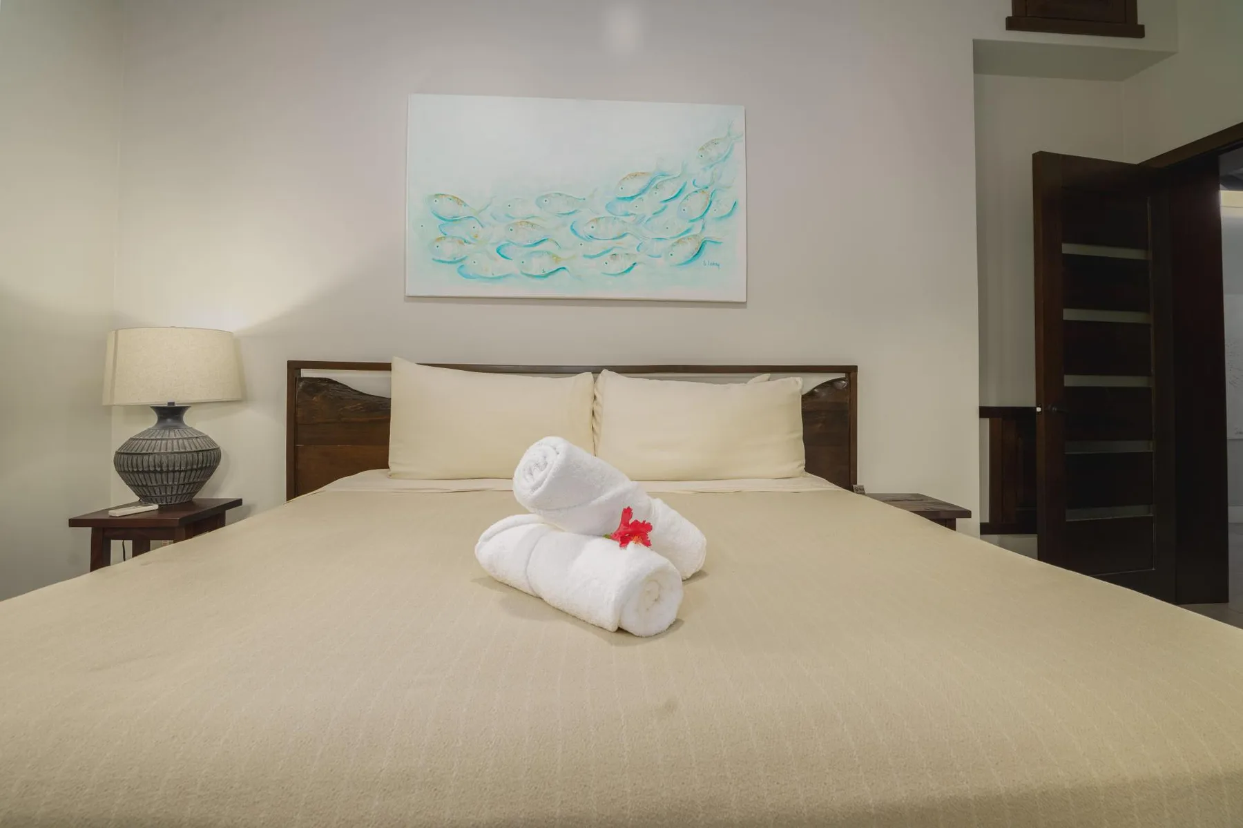 A bedroom with a neatly made bed and folded towels.