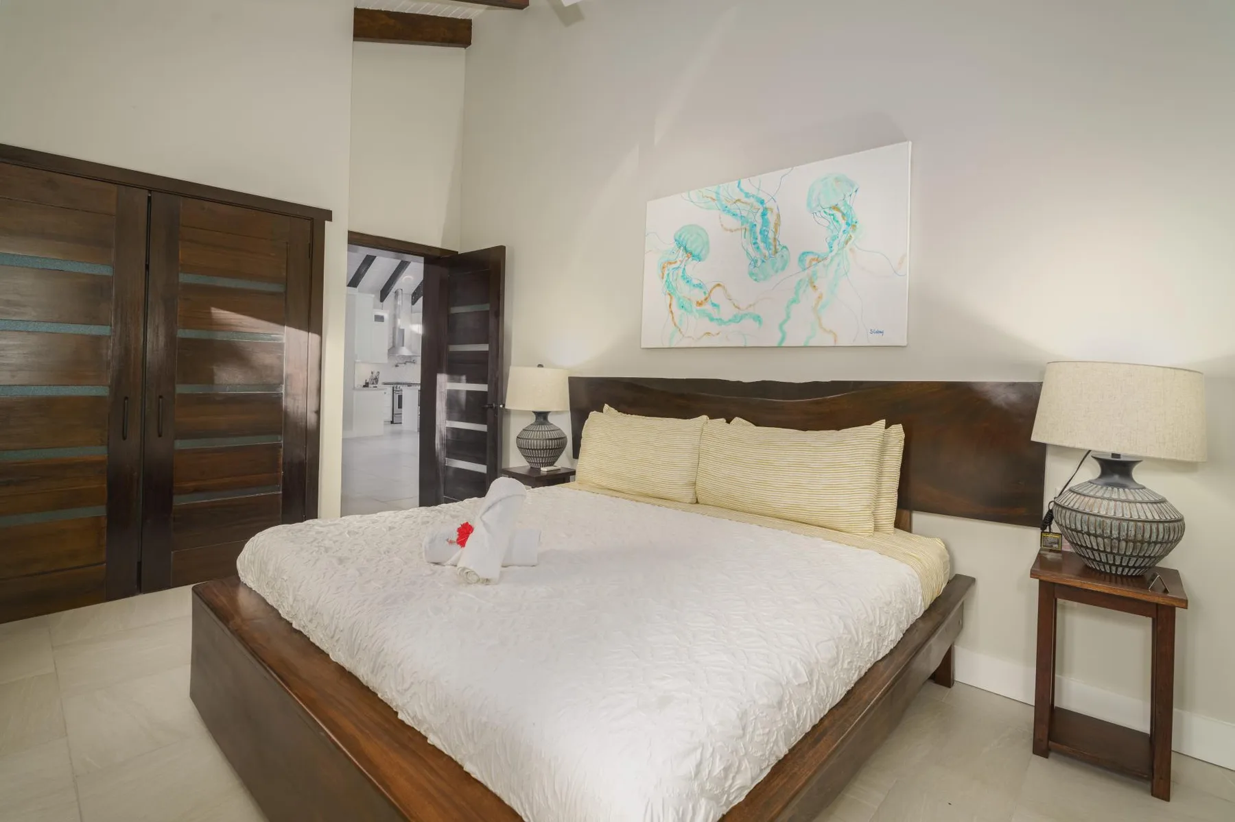 A bedroom with a bed, bedside tables, and framed artwork above the headboard.