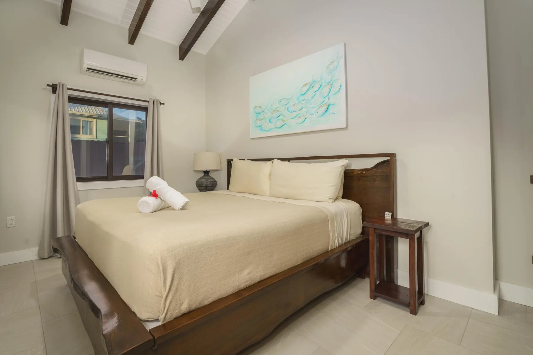 A bedroom with a neatly made bed beneath a painting.