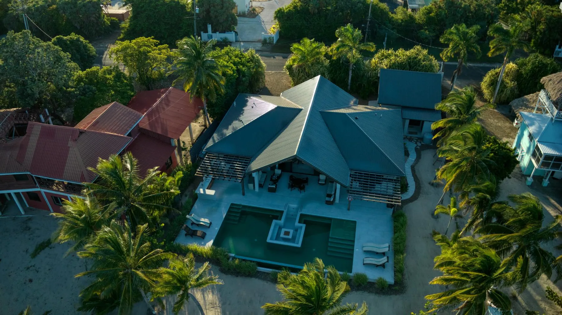 An aerial view shows a large house with a swimming pool surrounded by trees.