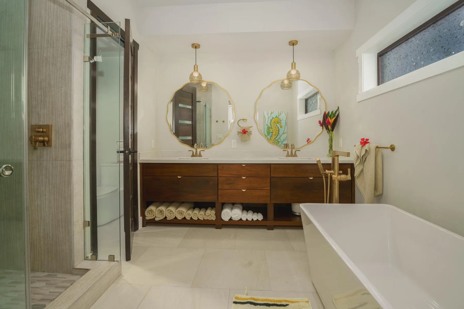 A bright bathroom with a double vanity, two mirrors, and a bathtub.