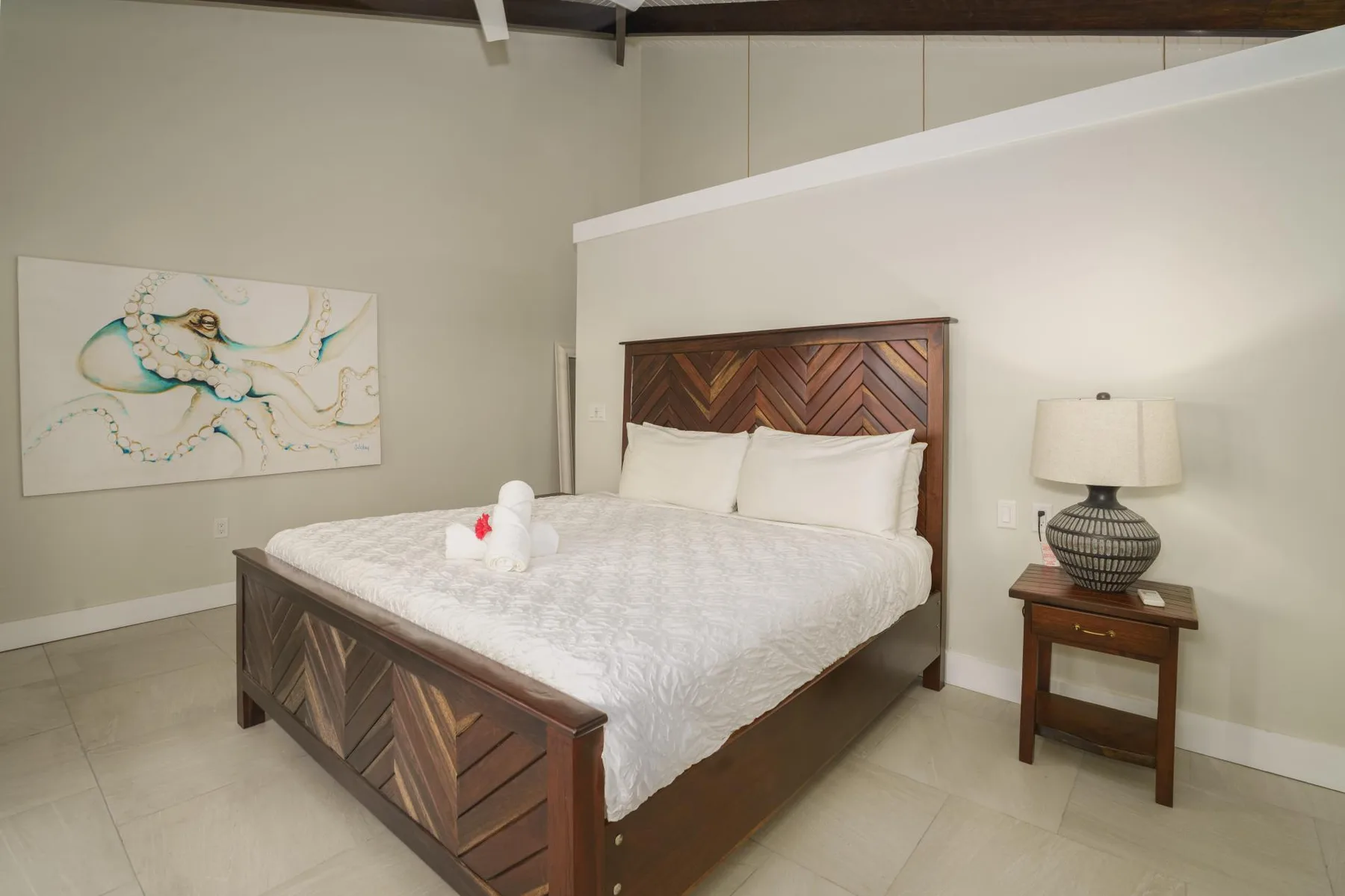 A bedroom with a wooden bed, white bedding, and wall art.