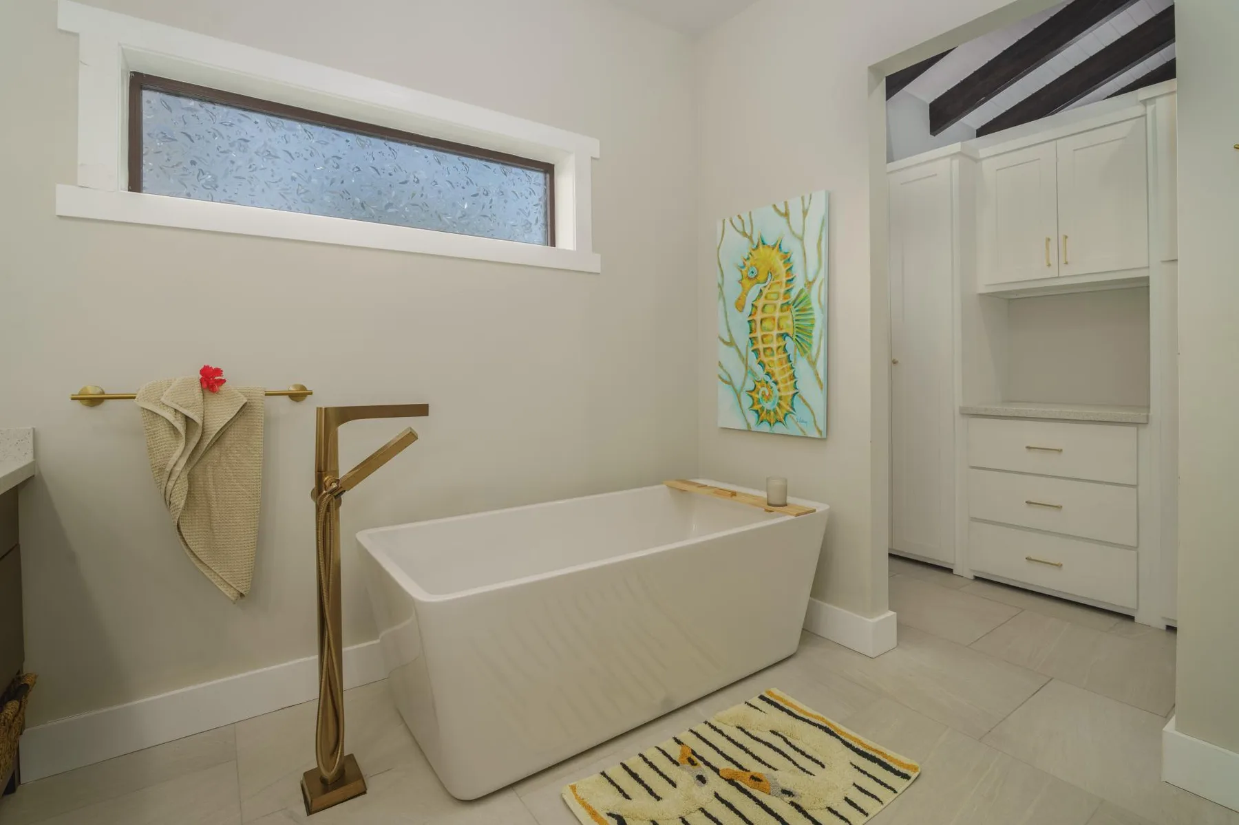 A bathroom with a freestanding bathtub, wall art, and a towel rack.