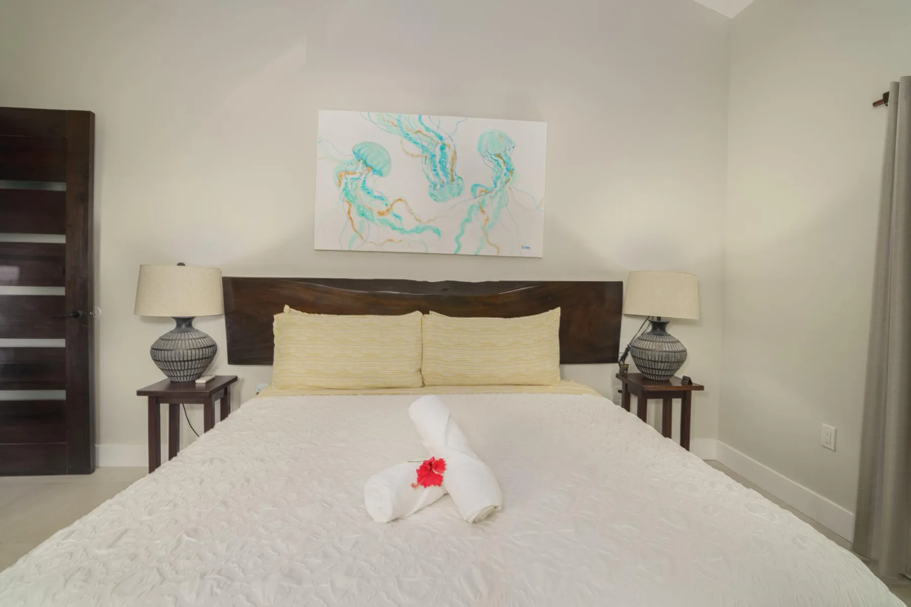 A bedroom with a bed, matching bedside lamps, and artwork above the headboard.