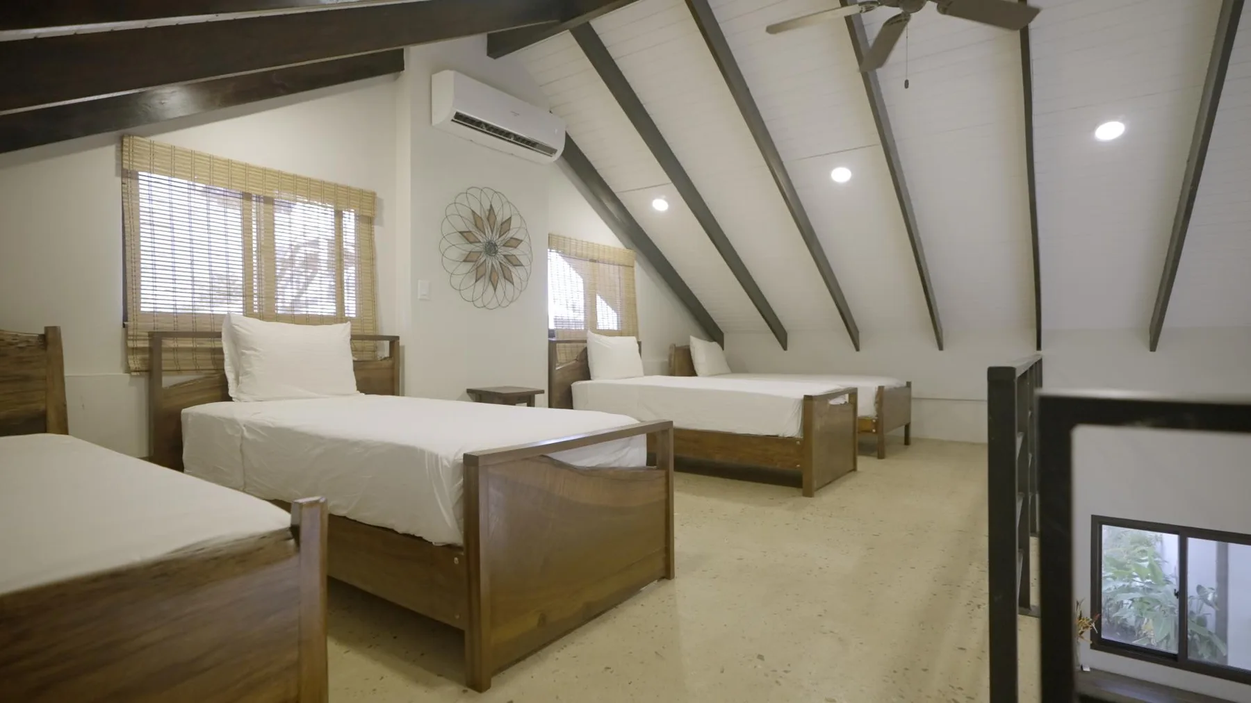 An attic bedroom with several wooden beds beneath sloped ceilings.