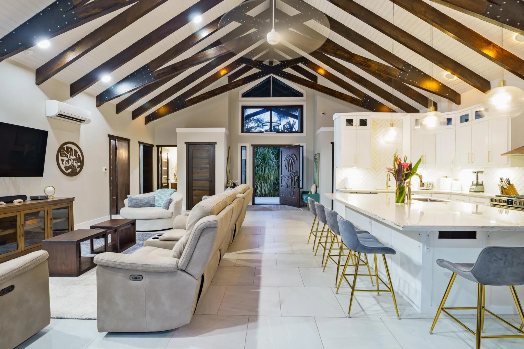An open-plan living room and kitchen with a vaulted ceiling and island seating.