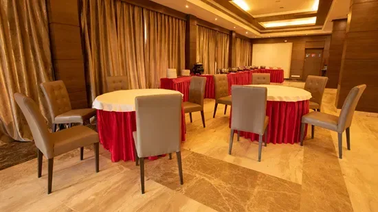 Representative hotel space: A banquet room has round tables with red skirts and upholstered seating.
