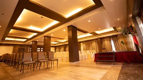 Representative hotel space: A warmly lit banquet room has rows of seating and a long table.