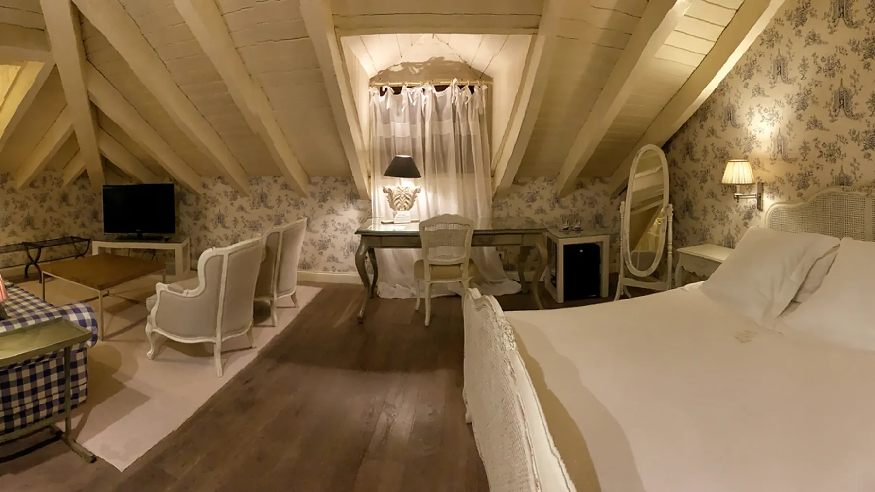Representative hotel space: A bedroom with a bed, seating area, and sloped ceiling.