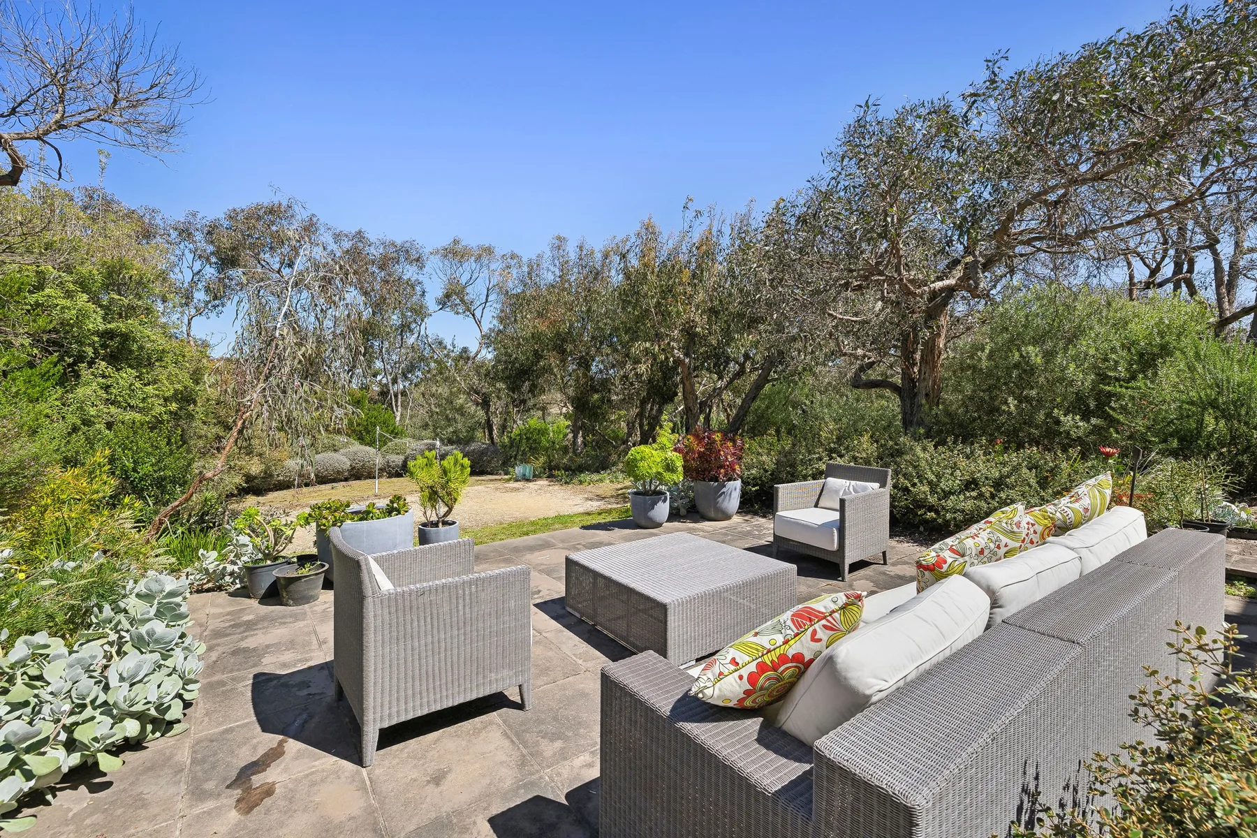 An outdoor patio seating area overlooks a landscaped garden.